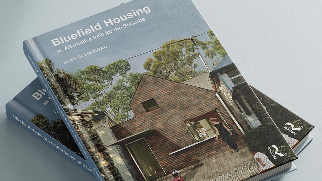 A photograph of two copies of the hardback version of the book 'Bluefield Housing as Alternative Infill for the Suburbs' by Damian Madigan. One book is stacked on top of the other.