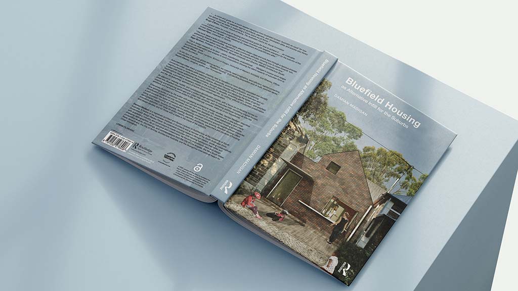 A photograph of the hardback version of the book 'Bluefield Housing as Alternative Infill for the Suburbs' by Damian Madigan, showing the book laying face down with the back cover on the left, and the front cover on the right.